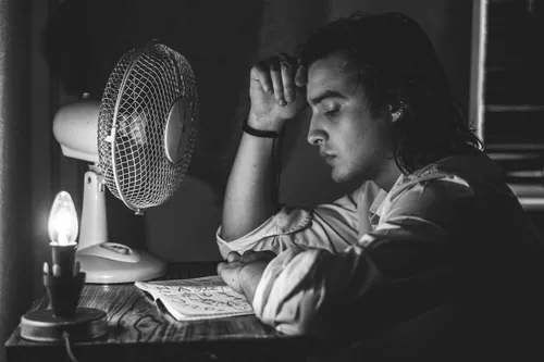 Black and white image of man reflecting in the dark with a notebook and pen
